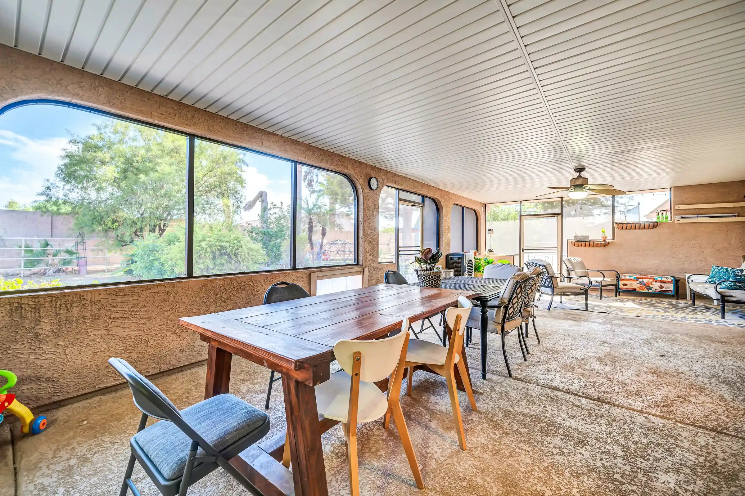 The sunroom's long wooden table with mismatched chairs, one folding chair turned out from the table.