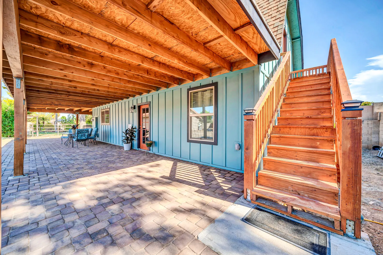 A red timber staircase and the long covered patio along the side of the barn.