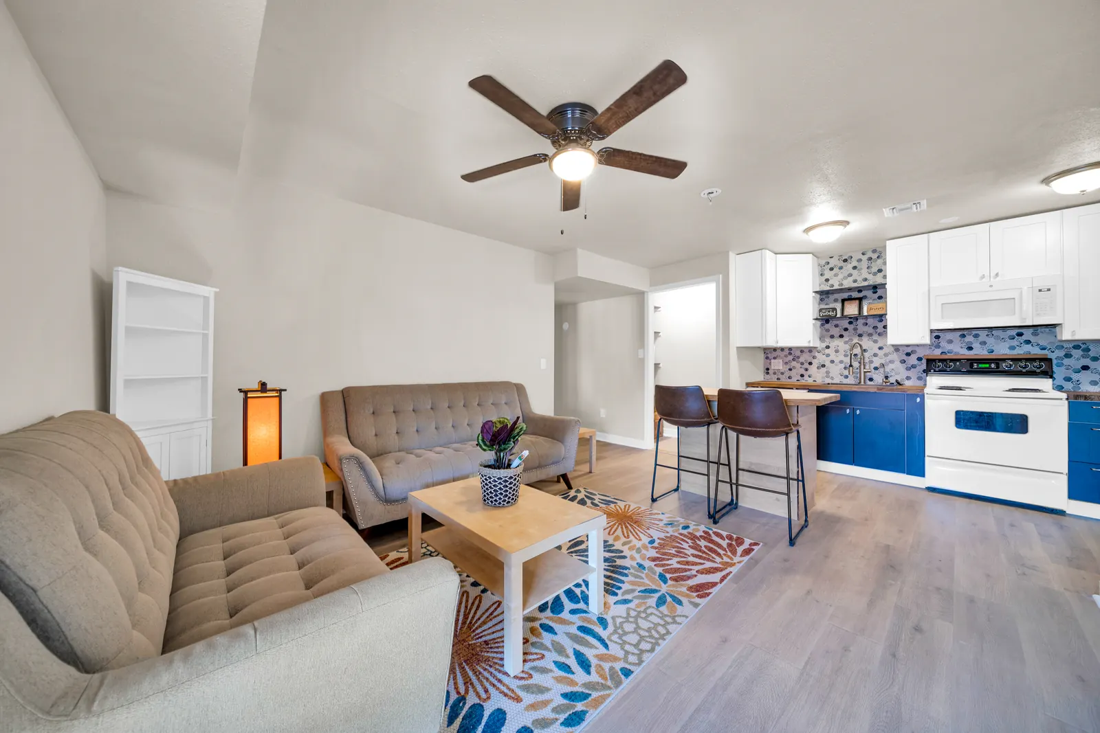 A living room with two sofas, a coffee table and an open kitchen with blue cabinets.